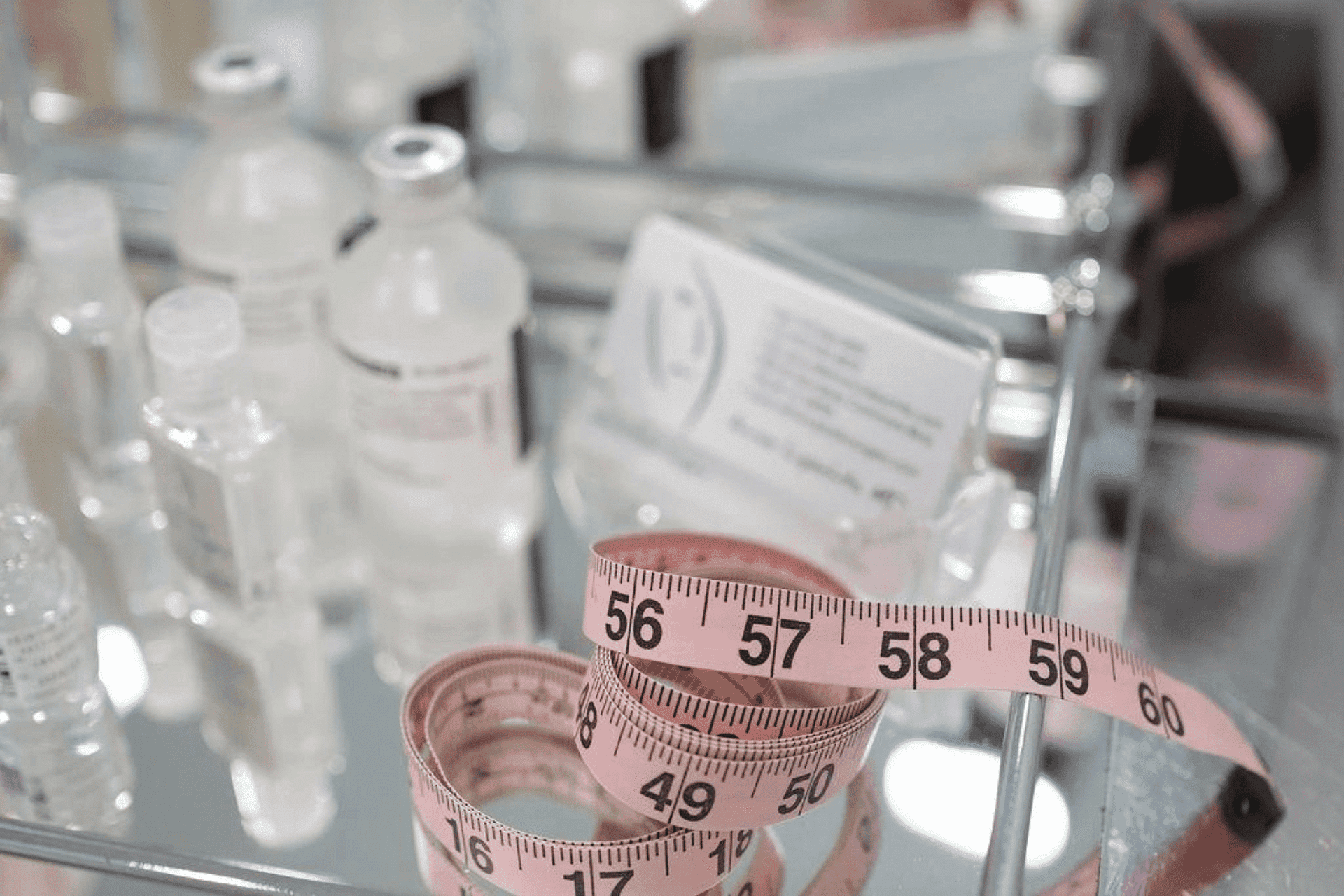A tape measure lying on a glass surface amidst beauty products.