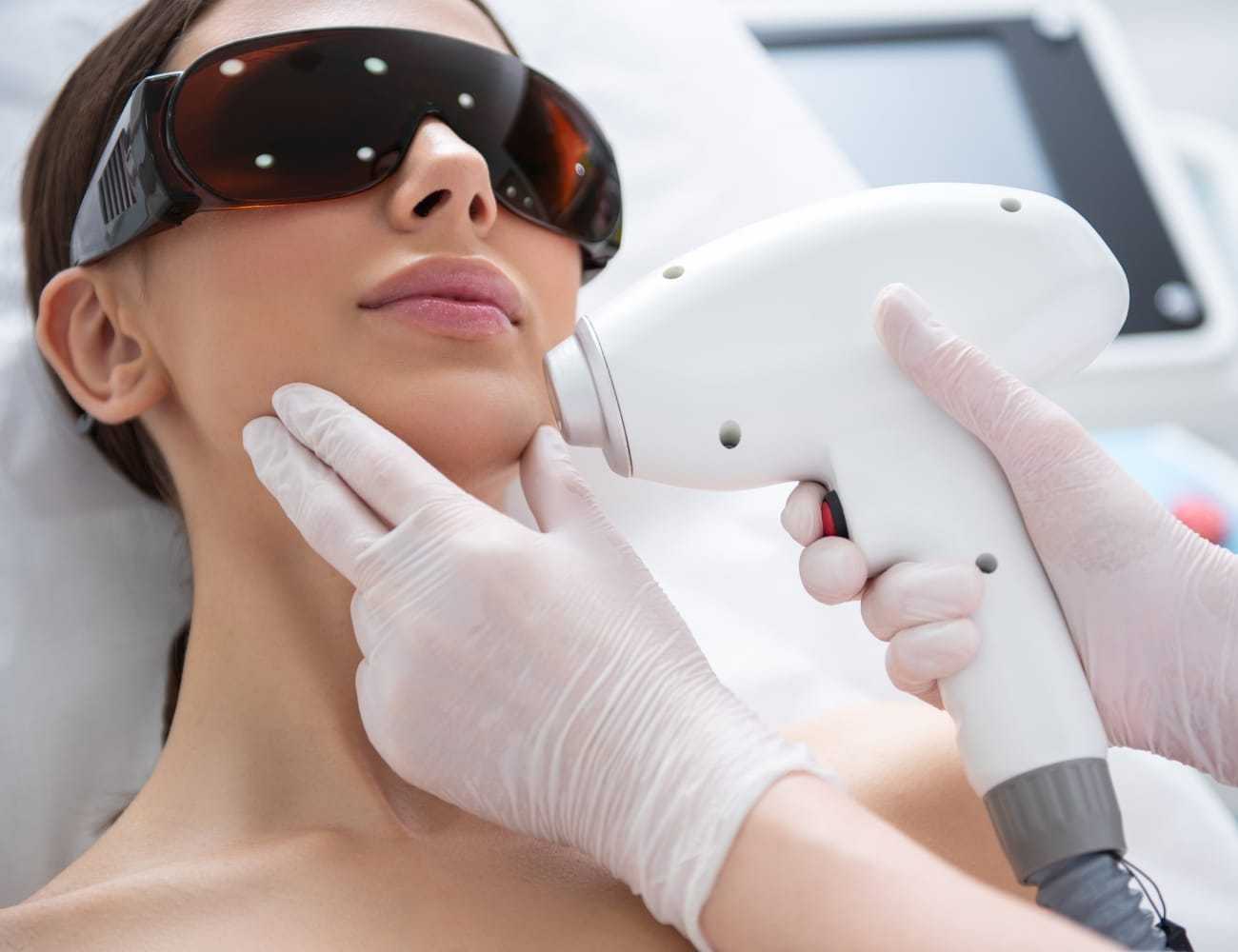 Woman receiving laser skincare treatment with protective eyewear.