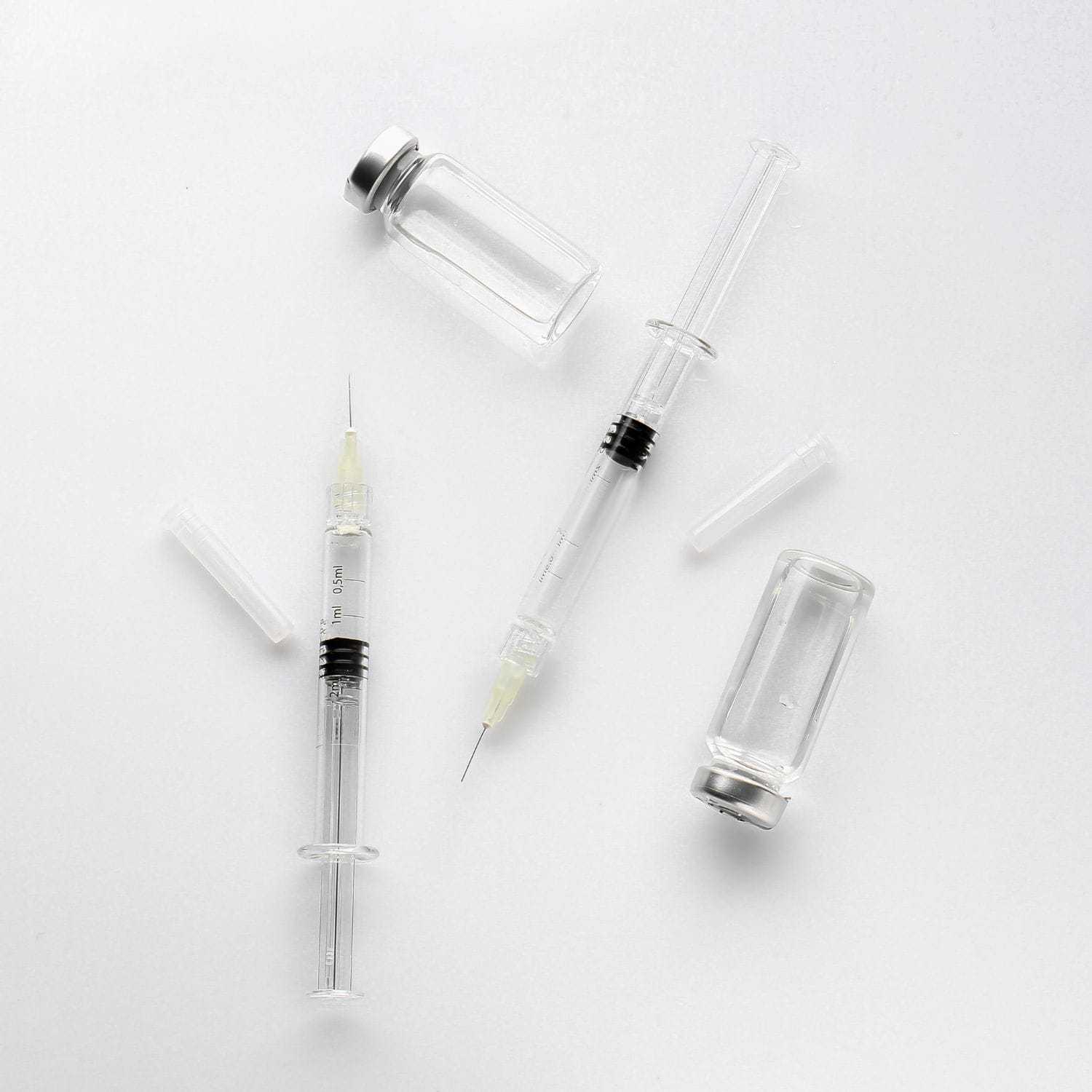 Medical syringes and vials on a white background.