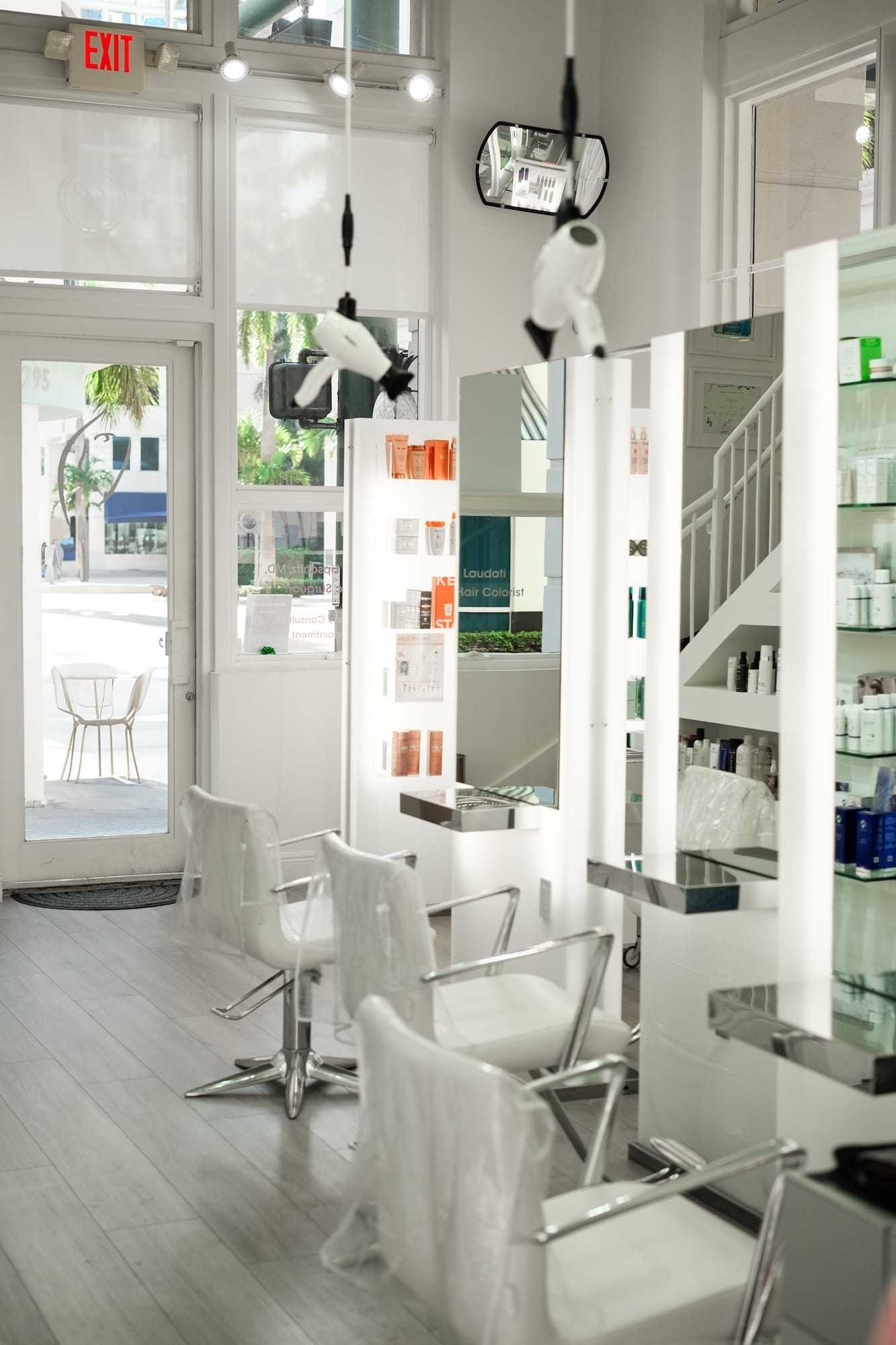 Modern hair salon interior with chairs, mirrors, and product shelves.