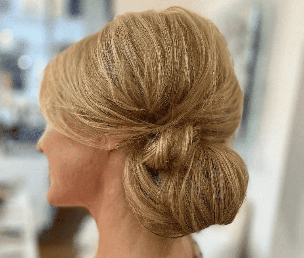 Elegant blonde chignon hairstyle from the side view.