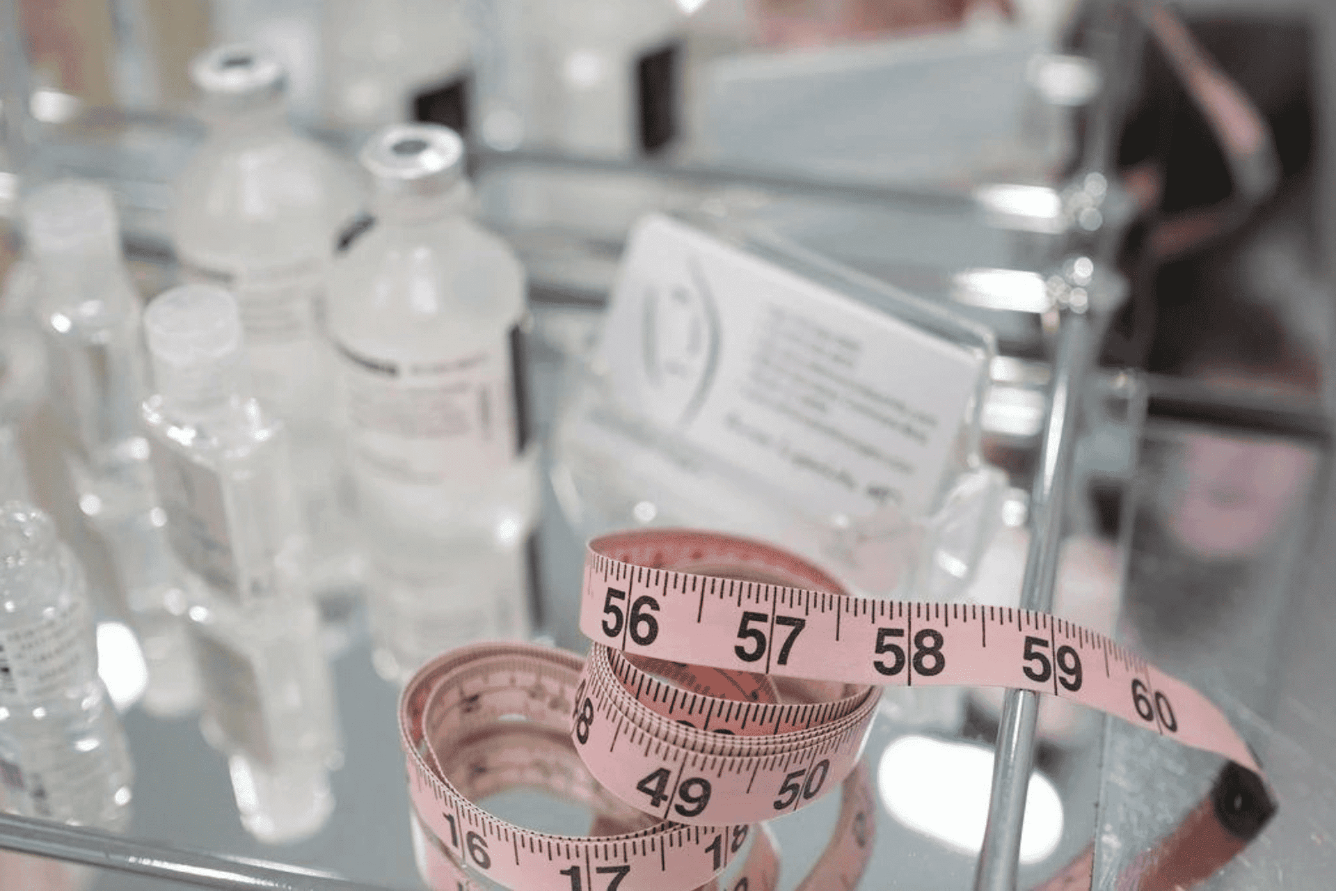 A tape measure lying on a glass surface amidst beauty products.