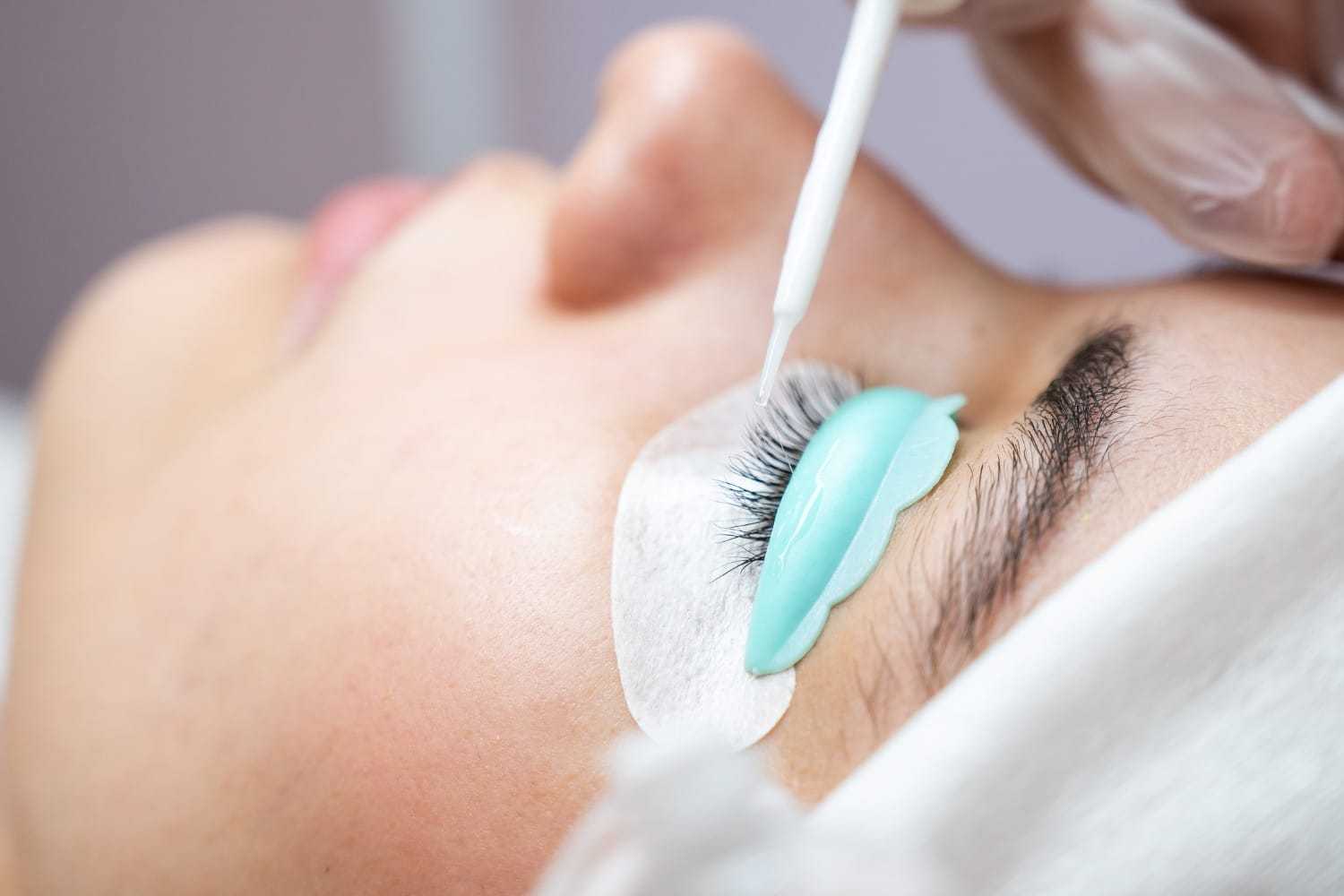 Close-up of eyelash extension procedure with adhesive application.