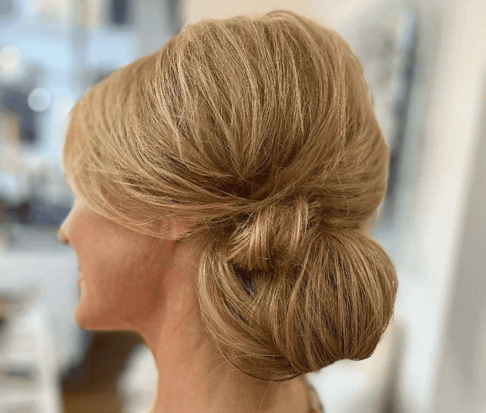 Elegant blonde chignon hairstyle from the side view.